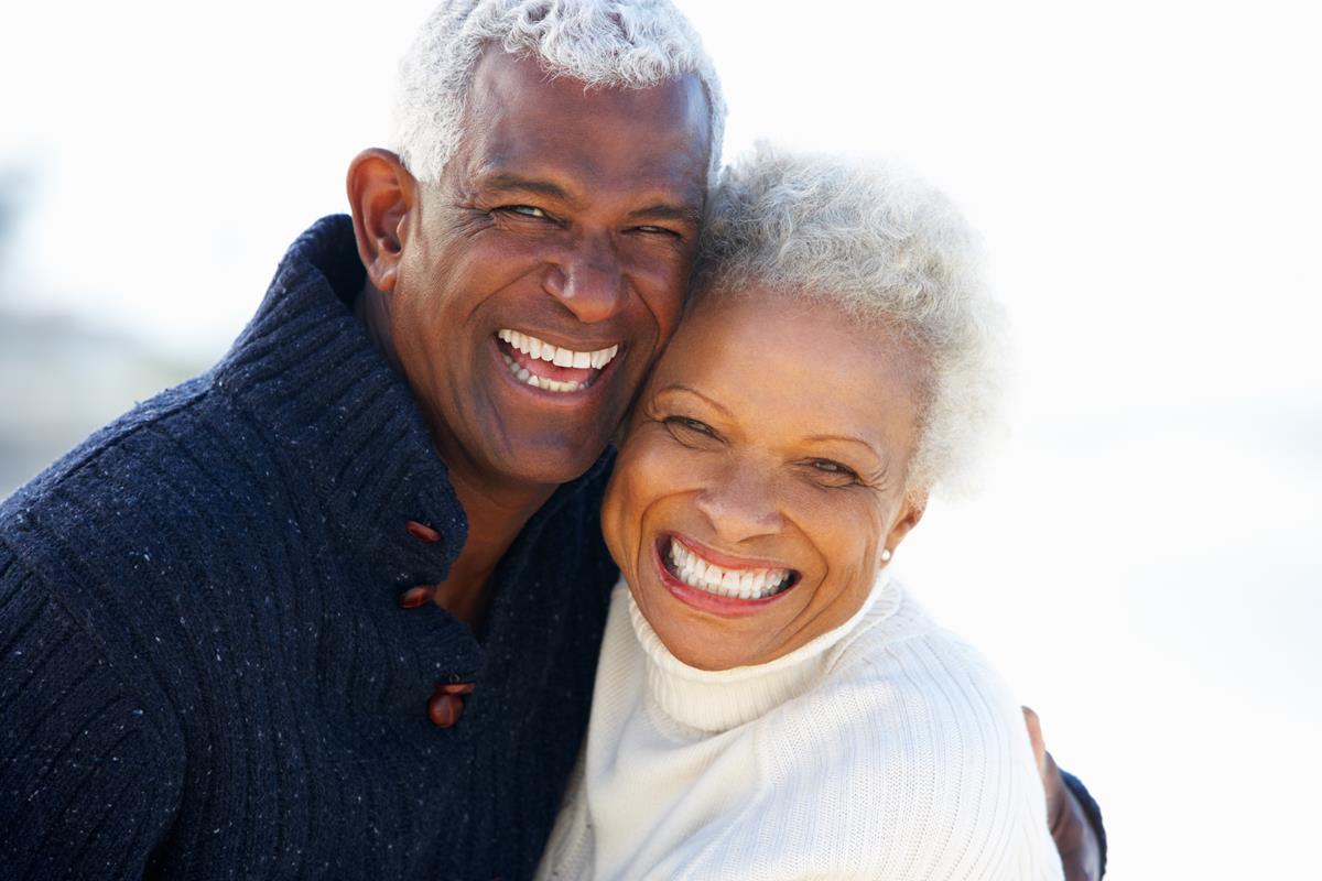 Older couple smiling outside together.