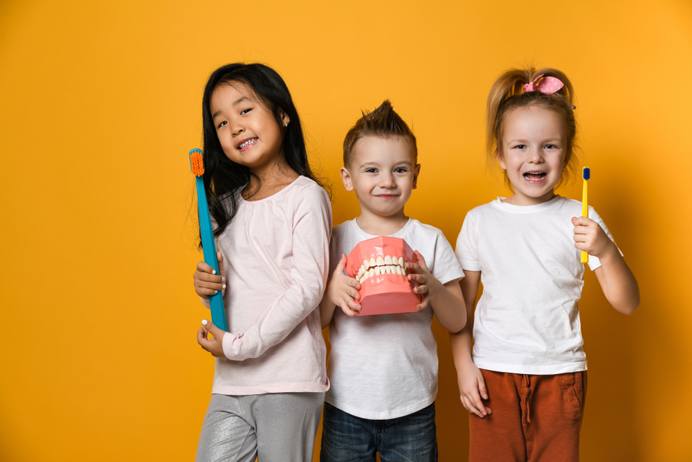 pediatric dentistry, children dentistry, three children holding up dental items