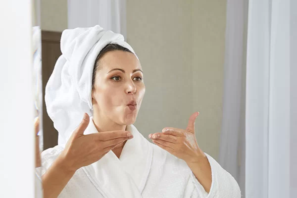 woman practicing mouth and throat exercises in front of her mirror