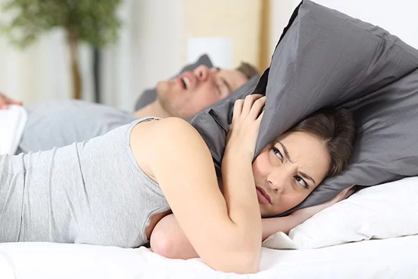 woman annoyed by her bed partner's loud snoring